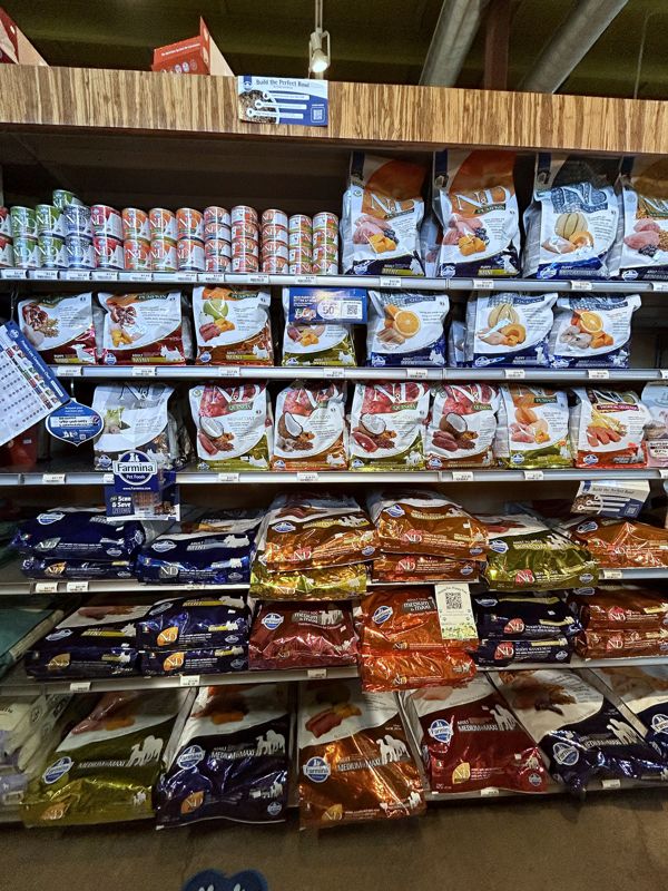 Shelves stacked floor to ceiling with bags of dog and cat food and cans up top